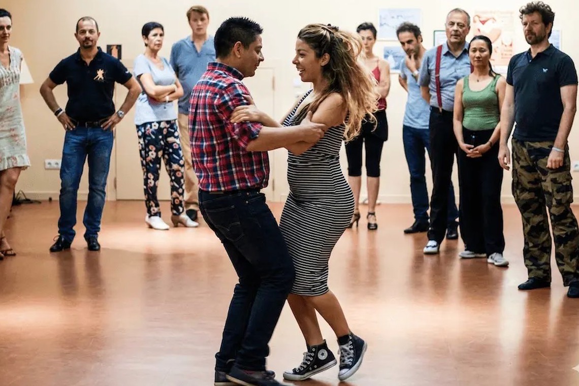 Un cours de tango chez BE-TANGO à Bruxelles : un couple danse pendant que le groupe regarde.